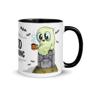 A cozy Halloween-themed ceramic Good Mourning Mug featuring an adorable cartoon ghost wrapped in a blanket, sitting on a gravestone with the words "RIP," sipping from a small pumpkin mug, with bats flying in.
