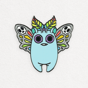 A quirky and colorful Bindlewood Shop Rainbow Mothbunny pin featuring a whimsical creature with a light blue body, big purple eyes, leaf-like ears, and wings adorned with skull patterns.