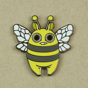 A whimsical Bindlewood Shop Lemon Bee pin depicting a cheerful, cartoon-style bee with big eyes and two antennae on a plain background, designed by Amanda Louise Spayd.