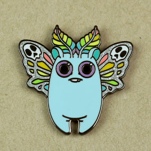 An enamel pin featuring a whimsical Rainbow Mothbunny design by Bindlewood Shop with a light blue body, large round purple eyes, leaf-like accents on its head, and decorative, skeleton-inspired wings.