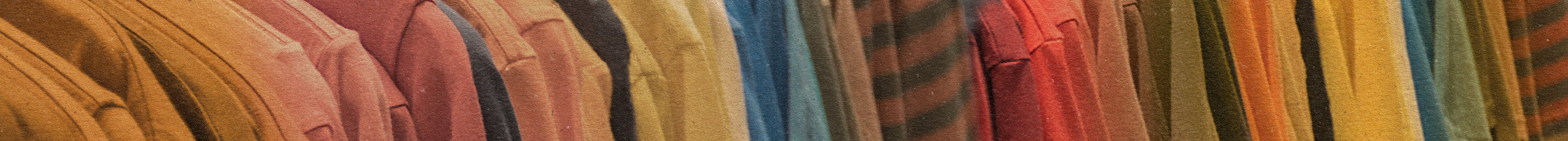 A row of colorful garments in shades of brown, yellow, orange, and red hang closely together on a rack, creating a warm and textured display.