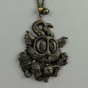 The Bindlewood Shop Painted Krampus Ornament, designed by Chris Ryniak, is a whimsical bronze creature with large eyes, curled horns, pointed ears, and festive details like a bundle of sticks, a jingle bell, and a hand-painted resin bucket.