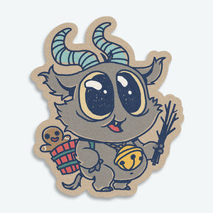 The Krampus Sticker (3-inch) from Bindlewood Shop features a cute creature with blue striped horns, shiny eyes, a bell necklace, and twigs. It carries a basket with a smiling gingerbread for an adorable holiday vinyl sticker design.