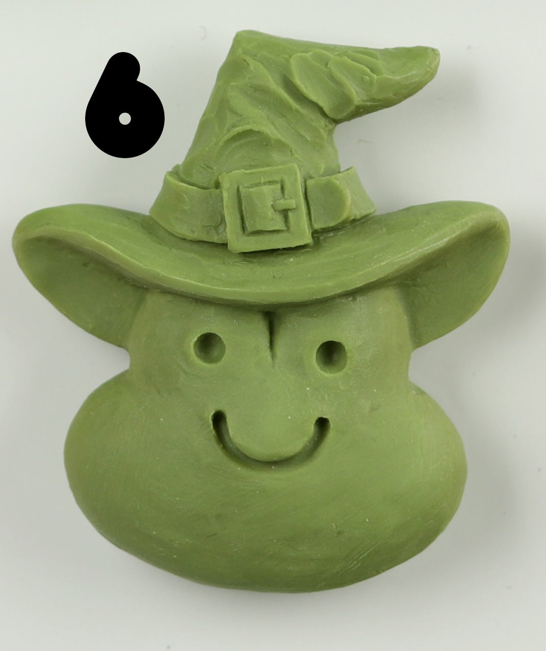 The Bindlewood Shop Halloween Magnets feature a hand-sculpted green clay smiling face with a pointed witch hat and buckle, accented by a bold black number 6 near the top left corner.