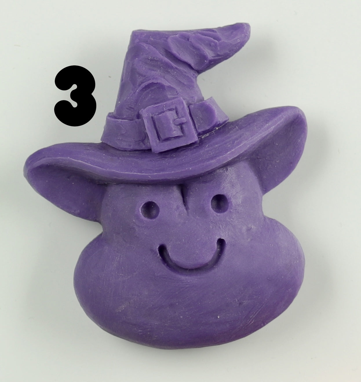 A purple, smiling blob-shaped Halloween Magnet from Bindlewood Shop, hand-sculpted with a pointed witch hat and buckle. Bold black number 3 is displayed to the left of the figure.