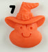 A Halloween Magnet by Bindlewood Shop shaped like an orange smiling face wearing a witch hat with a buckle, featuring a black number 7 in the top left corner.