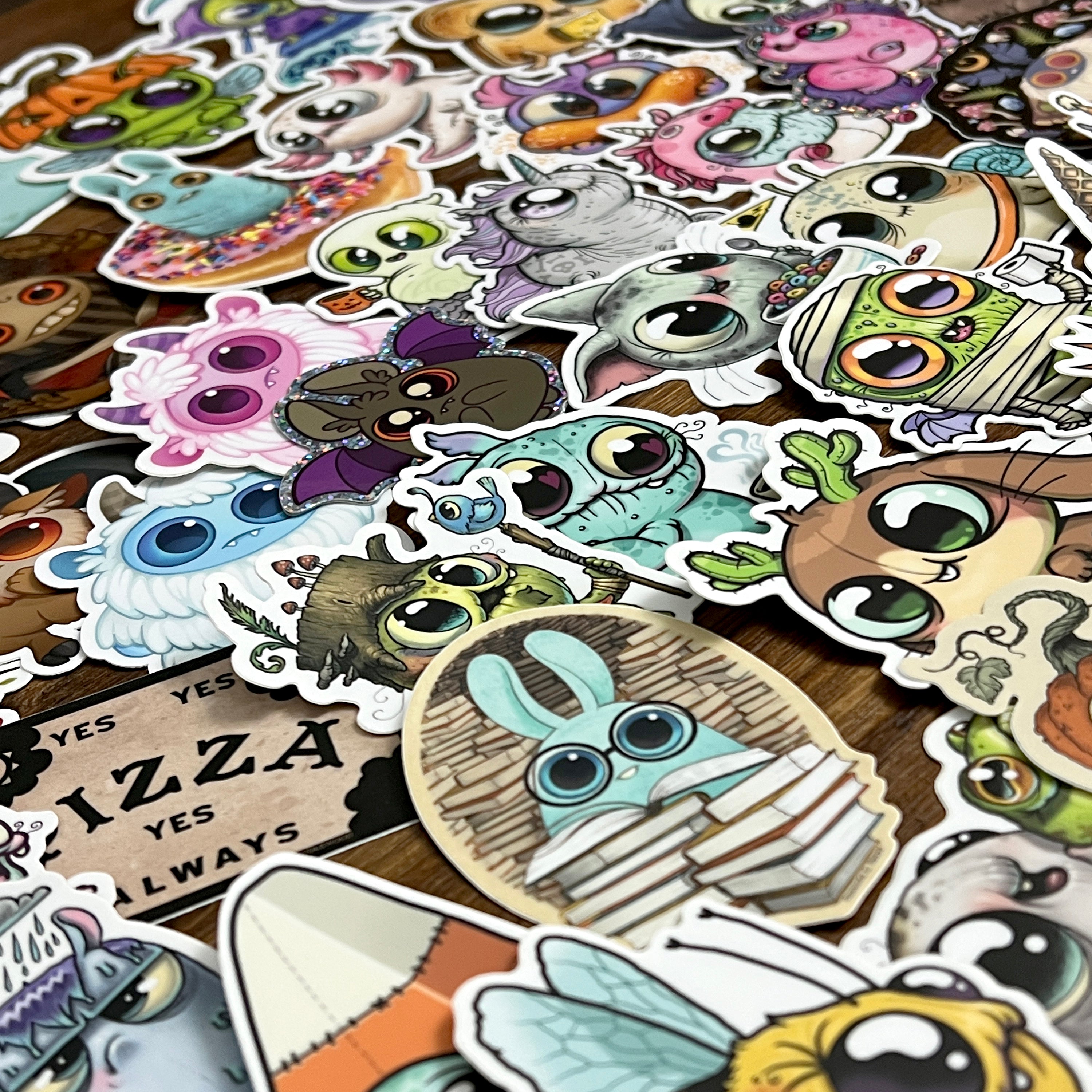 Brighten any space with the ULTRA MEGA STICKER PACK! from Bindlewood Shop—a delightful assortment of colorful vinyl stickers showcasing cute, big-eyed fantasy creatures, whimsical animals, and charming characters with expressive faces, all perfect for adding playful energy to your favorite surfaces.