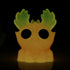 The Electric Peach Moose by Bindlewood Shop is a whimsical resin figure that glows in the dark. It features large eye holes and leaf-like green ears on its orange head, evoking a playful moose. The speckled texture adds charm, while the darkness highlights its glow-in-the-dark effect.