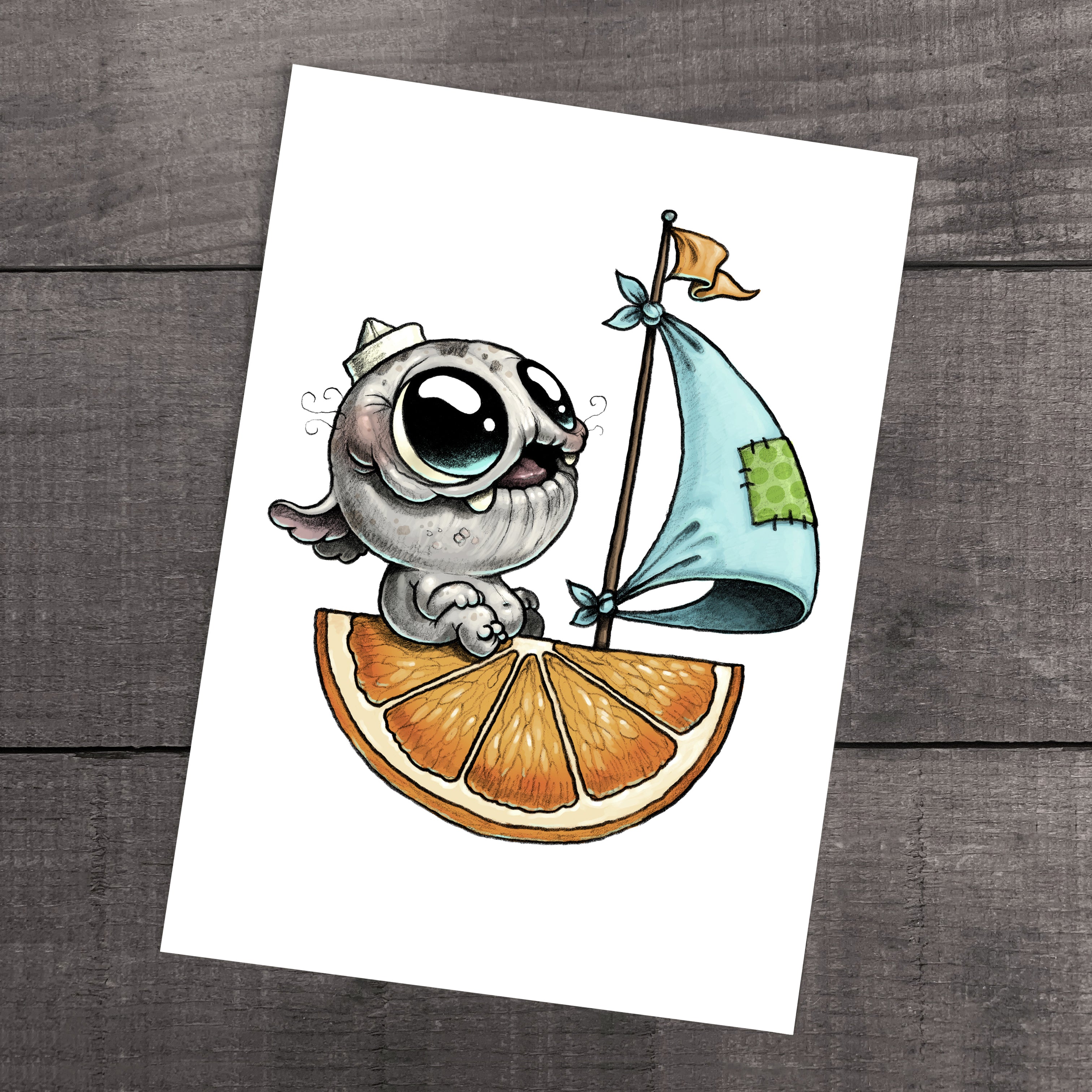 Vitamin Sea" Print by Chris Ryniak: a whimsical fine art print of a wide-eyed gray kitten sailing an orange-slice boat with a blue sail, on archival paper and set against a wooden background.