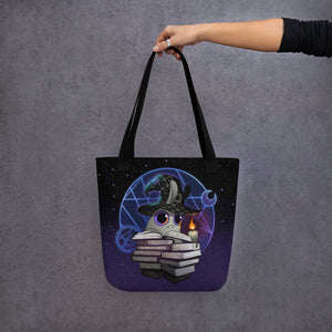 A hand holds the Neon Witchbunny Tote by Bindlewood Shop, adorned with a whimsical witch bunny and mystical symbols against a starry backdrop—perfect for fans of enchanting art.