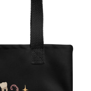 Close-up of the top corner of the Bindlewood Shop Moth Magic Tote, a sturdy tote bag in black weather-resistant fabric with a textured strap and partial white, pink, and yellow designs.