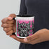 A person holds a black and white Radbit Mug by Bindlewood Shop, featuring a cartoonish, fierce bat-like creature design against a pink background.