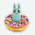 A blue, wide-eyed Pipsqueak with bunny ears sits in a pink-frosted, sprinkle-topped donut in the Donut Pip Sticker by Bindlewood Shop.