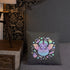 A decorative linen-textured Pastel Candy Bat Throw Pillow from Bindlewood Shop, featuring a cute, colorful central bat with two ghosts surrounded by pastel stars and flowers, rests on a gray bedspread. A nightstand with a wooden lamp and patterned wallpaper with animal motifs are in the background.