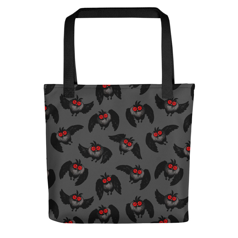The Mothman Cryptid Tote by Bindlewood Shop is a gray bag with black handles, showcasing a pattern of cartoon-style black owls with red eyes and outspread wings. The background is dark gray, and the design evenly covers the entire surface, evoking the feel of cryptid-hunting gear or an Amanda Louise Spayd creation.