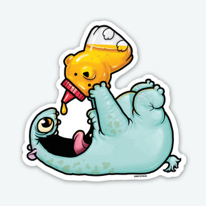 The Honey Bear Sticker from Bindlewood Shop features a vibrant cartoon image of a playful, blue creature lying on its back, joyfully holding a honey bear bottle over its open mouth with honey dripping out. The creature has one large green eye and appears to be happily anticipating the honey. This high-quality vinyl sticker is both durable and colorful.