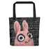 The Pipsqueak Math Tote by Bindlewood Shop features a pink, wide-eyed cartoon creature from the Dust Bunnies collection on a spacious tote with black handles. The bold black background is adorned with white mathematical equations and geometric shapes.