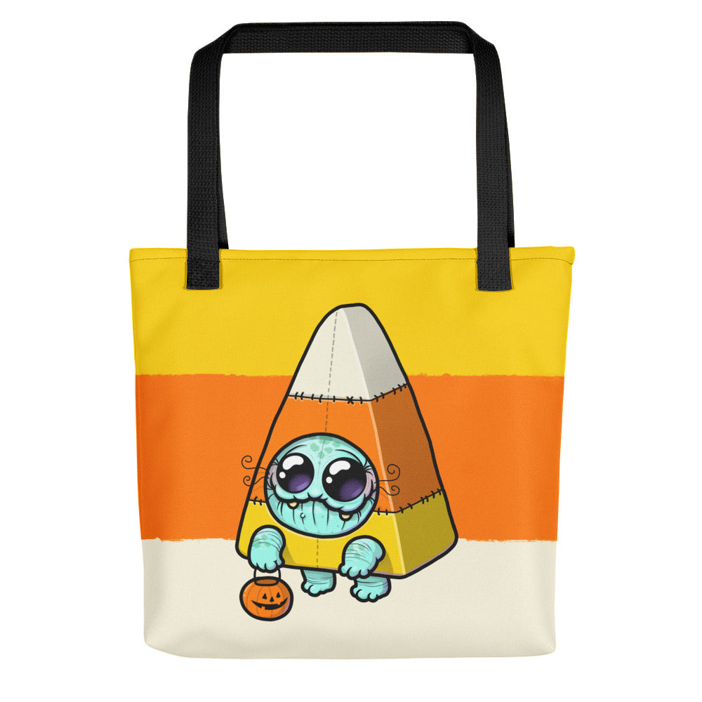 The Candy Corn Tote Bag by Bindlewood Shop is weather resistant and showcases a cute blue creature dressed as candy corn with a jack-o’-lantern bucket, set on yellow, orange, and cream stripes.