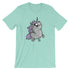 The Goth Ponycorn Tee from Bindlewood Shop is a light green T-shirt featuring a chubby, cute unicorn illustration at the center, made from high-quality fabric. The unicorn has a purple mane, a sparkling horn, and big, expressive eyes, giving it a whimsical and endearing appearance. The shirt boasts short sleeves and a gender-neutral fit with a round neckline.