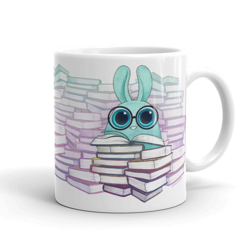 The "So Many Books Mug" from Bindlewood Shop features an adorable blue cartoon rabbit with oversized glasses, surrounded by stacks of vibrant books. Safe for use in both the microwave and dishwasher, this mug's whimsical design adds a cozy, bookish vibe to your everyday routine.